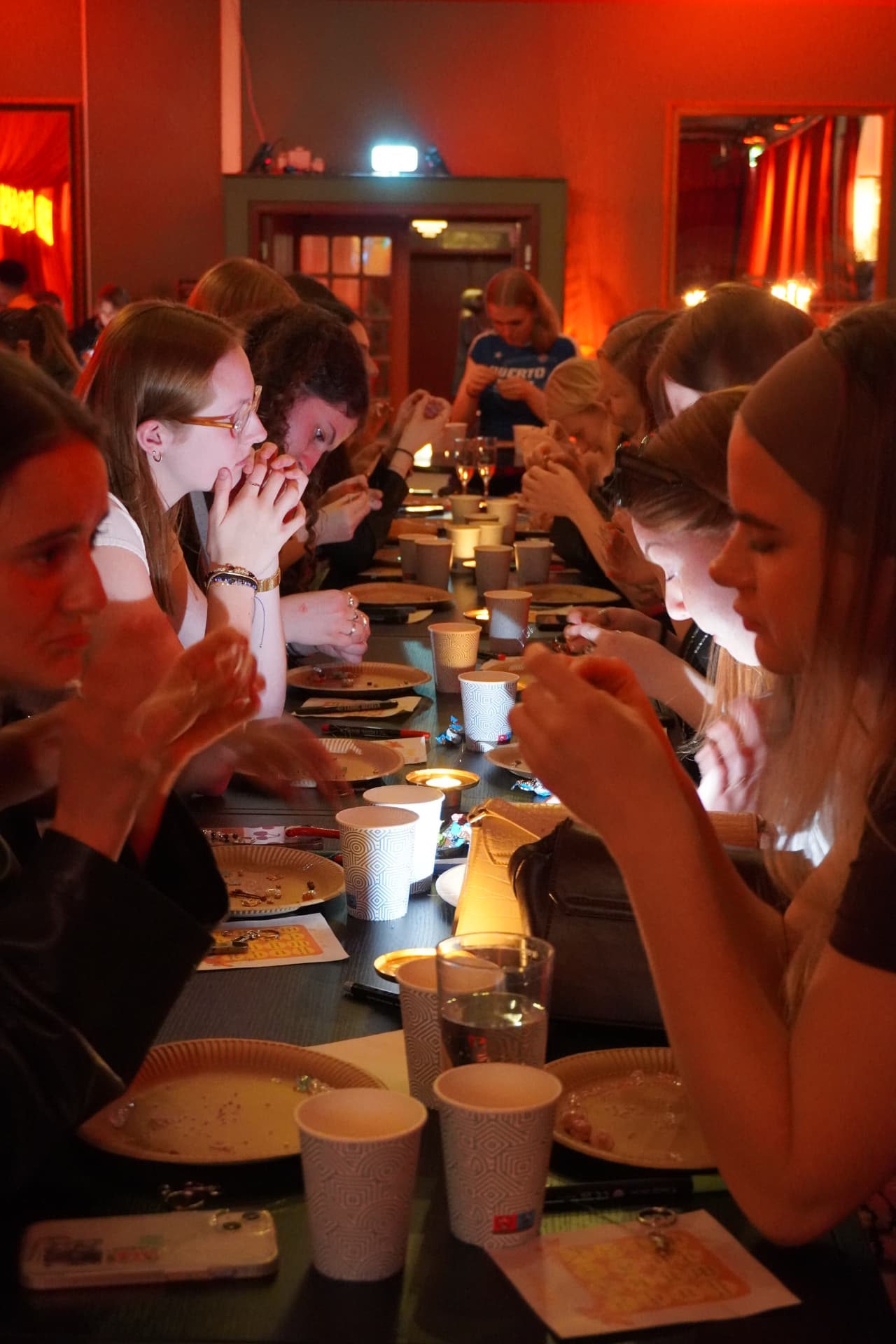 People gathered around a long table making crafts together in warm candlelight